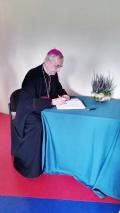 Arcybiskup Stanisław Gądecki wpisuje się do szkolnej Księgi pamiątkowej.